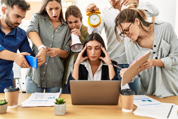 Stressed mortgage employee surrounded by demanding clients showing workplace pressure.